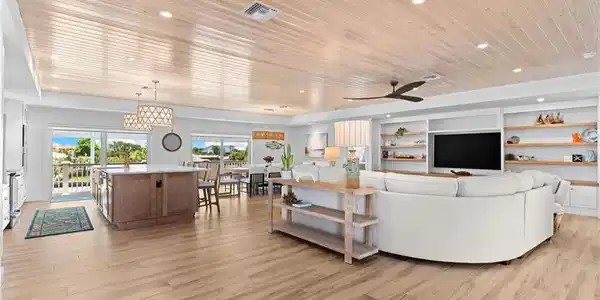 Image 4: Spacious open-concept living area featuring wood-finish flooring, a shiplap ceiling with recessed lighting, and a built-in media center with shelving