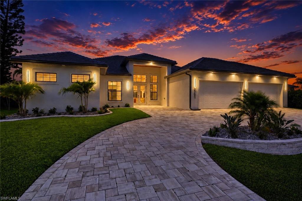 Image 3: Contemporary single-story residence featuring a paved driveway, a two-car garage with individual doors, and a manicured lawn