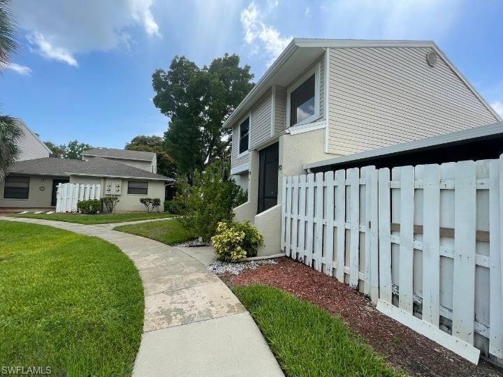 Image 2: Two-story exterior with light-colored siding and a white privacy fence