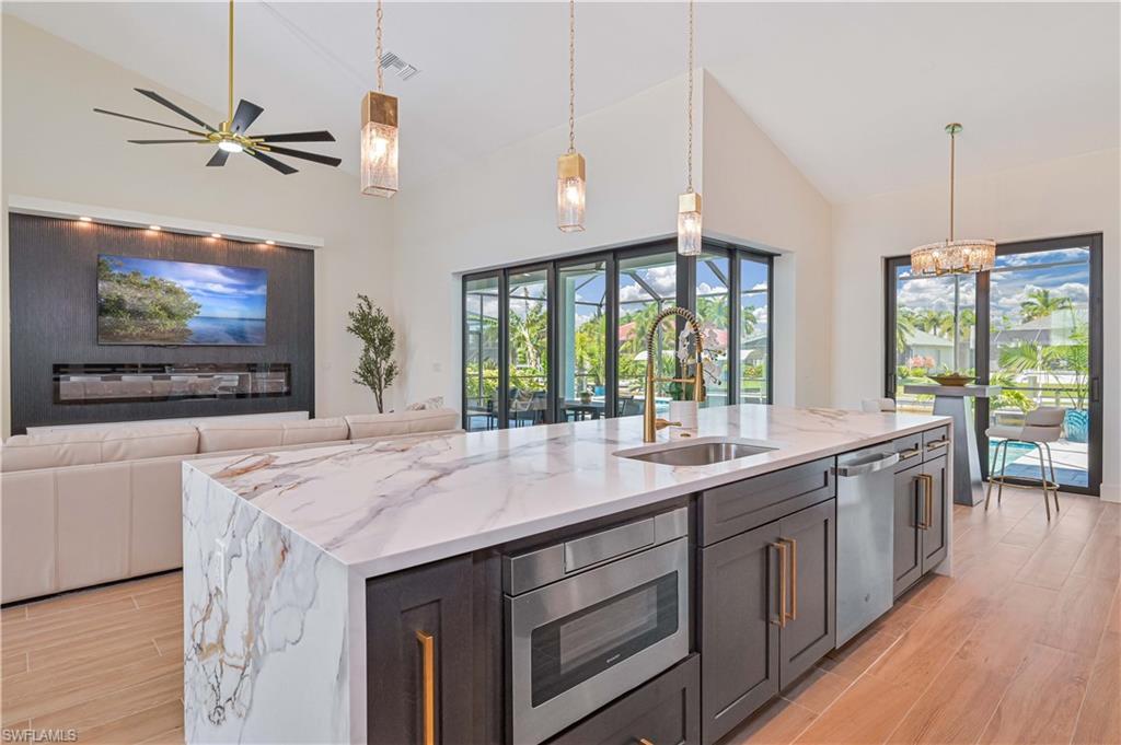 Image 4: Gourmet kitchen island with waterfall-edge countertop, undermount sink, and integrated microwave drawer