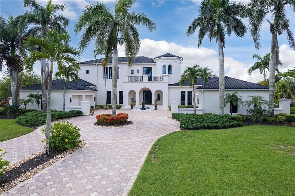 Image 2: Grand residence featuring a white stucco exterior, black tile roof, and a prominent turret element