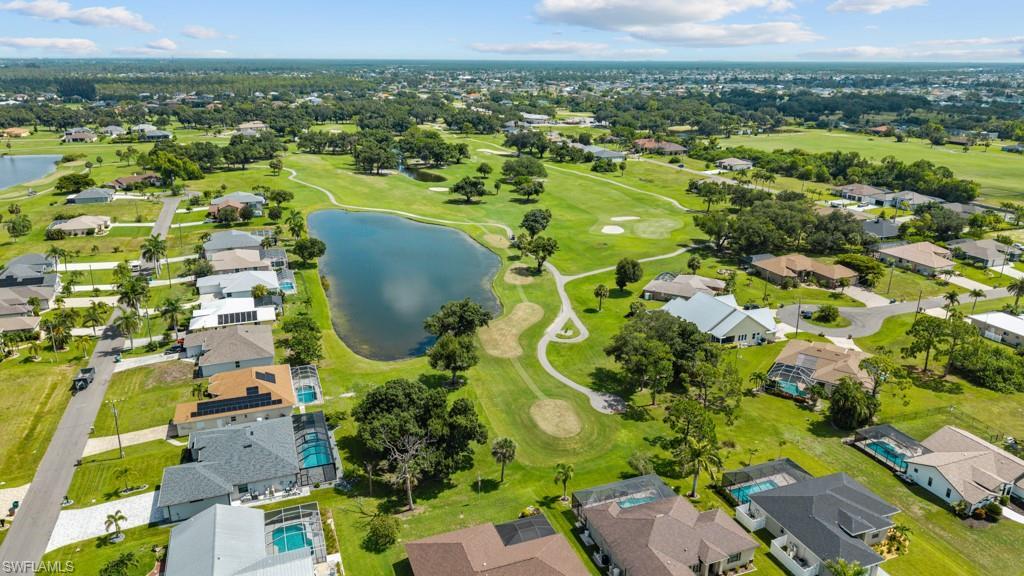 Image 4: Expansive golf course setting featuring a water hazard, surrounding residential properties, paved streets, and mature trees