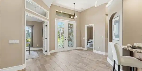 Image 3: Entryway featuring Wide wood-finish plank tile flooring, double French doors with decorative etched glass, and transom windows