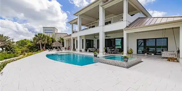 Image 2: Expansive poolside patio featuring a rectangular swimming pool and integrated spa with mosaic tile surround
