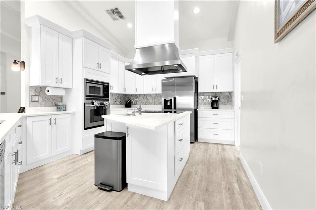 Image 3: The Fully Equipped Island Kitchen Comes With Upgraded White Wood Cabinets & Drawers, Quartz Countertops, Tile Backsplash, Stainless Steel Appliance With Stainless Steel Hood, Wall Oven, Microwave, Stainless Steel Sink, Bosch Instant Under The Sink Hot Water Heaters, And A Multi-Person Breakfast Bar!