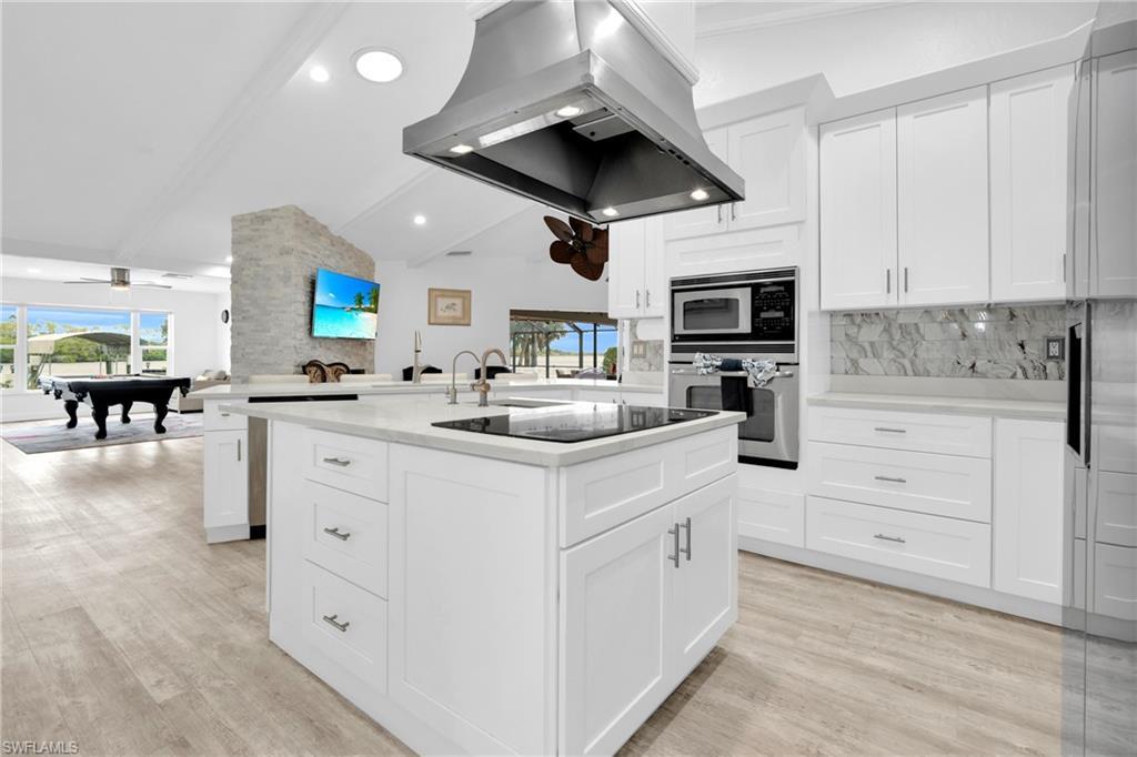 Image 4: The Fully Equipped Island Kitchen Comes With Upgraded White Wood Cabinets & Drawers, Quartz Countertops, Tile Backsplash, Stainless Steel Appliance With Stainless Steel Hood, Wall Oven, Microwave, Stainless Steel Sink, Bosch Instant Under The Sink Hot Water Heaters, And A Multi-Person Breakfast Bar!