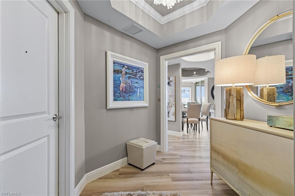 Image 1: Hallway with ornamental molding, light hardwood / wood-style flooring, and a raised ceiling