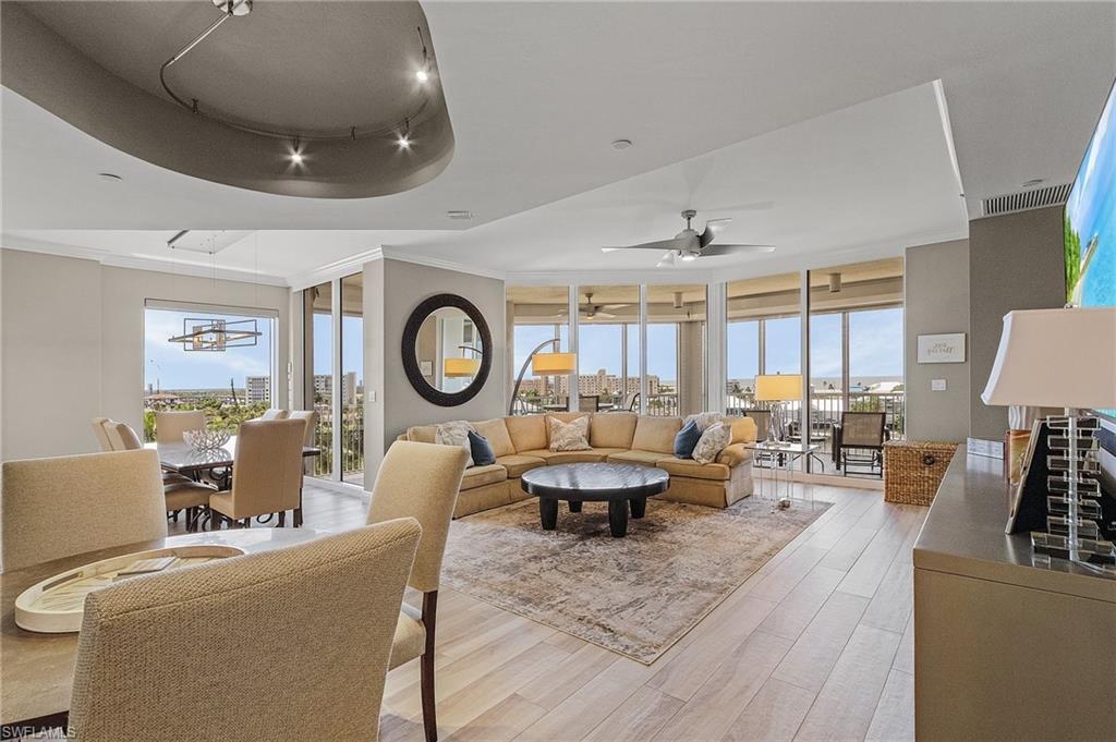 Image 2: Living room with a raised ceiling, light hardwood / wood-style flooring, a wealth of natural light, and ceiling fan