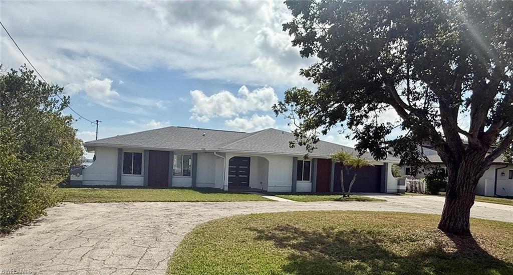 Image 2: Ranch-style house featuring driveway, a front lawn, an attached garage, and stucco siding