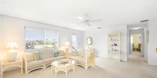 Image 3: Living area with a ceiling fan, visible vents, and carpet