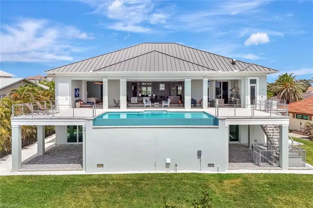 Image 1: Rear view of house featuring outdoor lounge area, a standing seam roof, a patio, and stairs