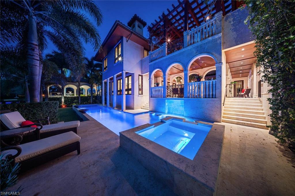 Image 4: Pool at twilight with a balcony, a patio area, and a pool with connected hot tub