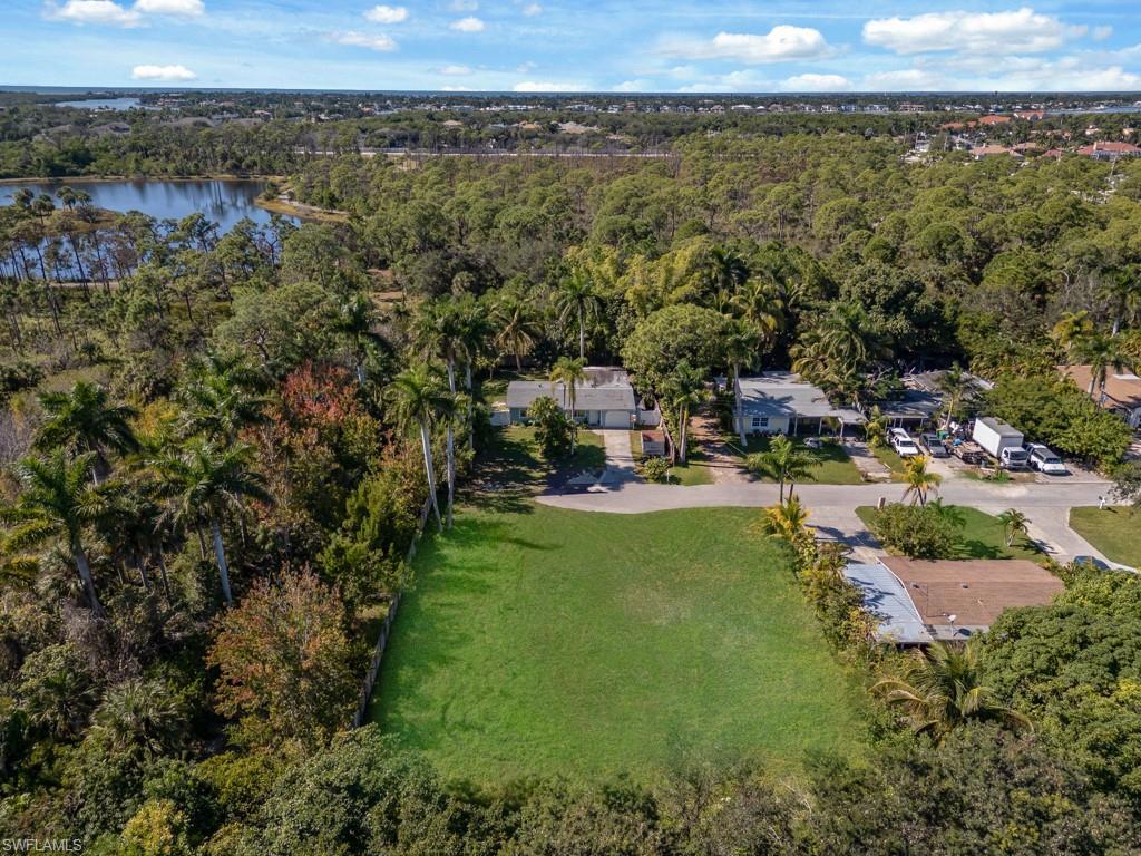 Image 4: Aerial overview of property's location featuring a heavily wooded area and a nearby body of water