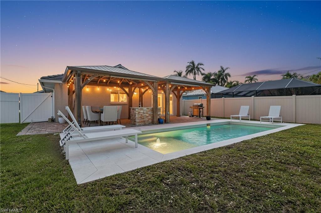 Image 2: Back of house at dusk with a gate, a fenced backyard, a gazebo, and stucco siding