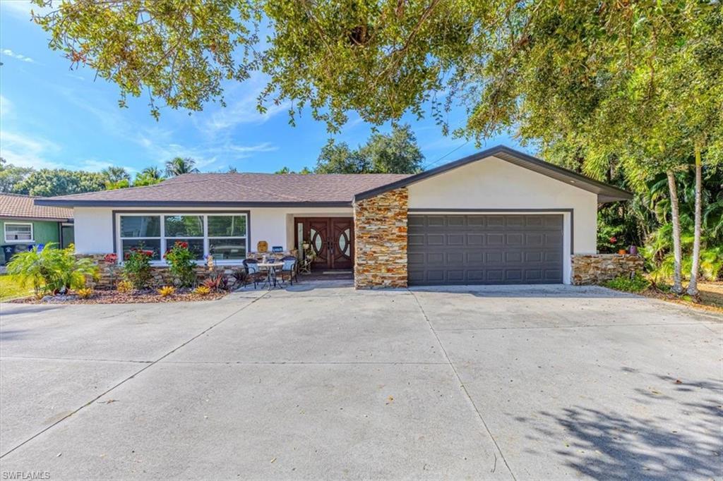 Image 2: Ranch-style home featuring stucco siding, stone siding, driveway, and an attached garage