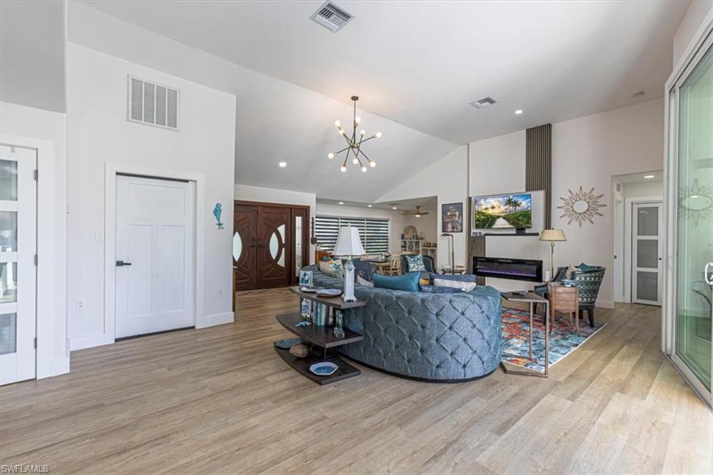 Image 3: Living area with a chandelier, light wood finished floors, a ceiling fan, recessed lighting, and high vaulted ceiling