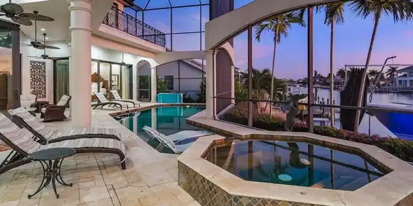 Image 4: Pool at dusk with an in-ground hot tub, a lanai, an outdoor pool, and a sunroom