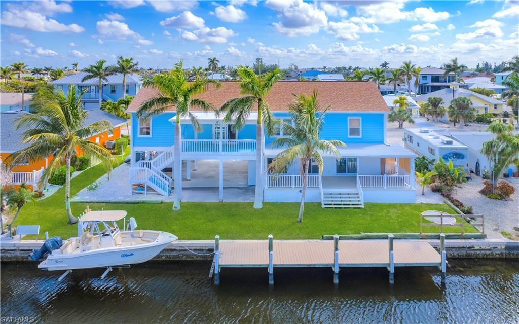 Image 2: Rear view of house with a yard, a water view, a patio area, and boat lift
