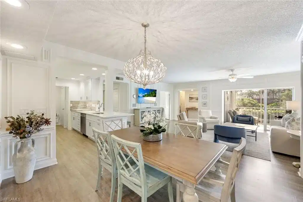 Image 1: Dining area with a textured ceiling, light wood-type flooring, a decorative wall, a ceiling fan, and a chandelier