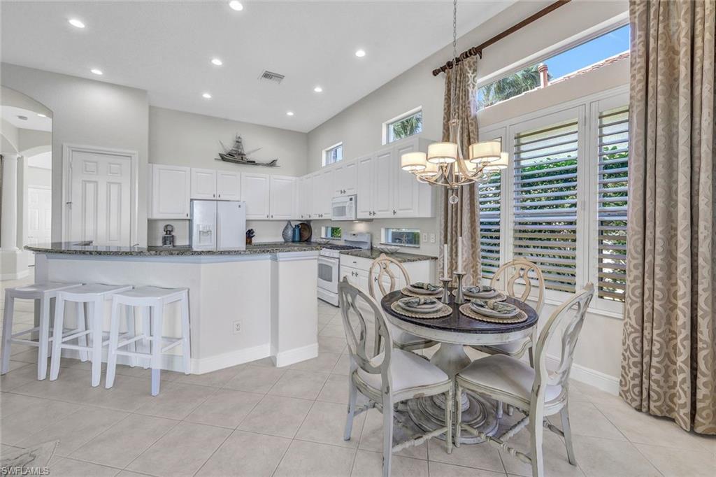 Image 4: Kitchen featuring white appliances, white cabinetry, light tile patterned floors, and dark stone counters