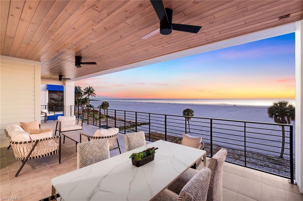 Image 1: Patio terrace at dusk with ceiling fan, a patio, an outdoor living / dining area, and a water view - Virtually Edited Image