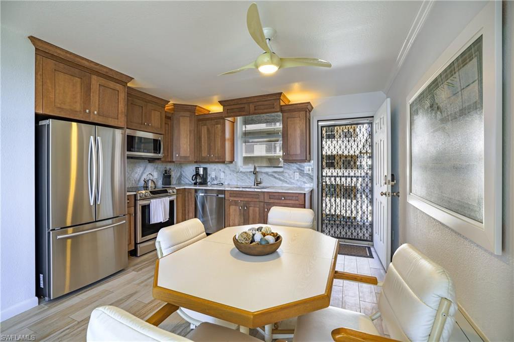Image 2: Kitchen featuring stainless steel appliances, a ceiling fan, tasteful backsplash, and light wood-style flooring