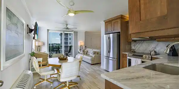 Image 4: Kitchen with stainless steel appliances, wood finish cabinetry, light wood-style flooring, open floor plan, and light stone countertops