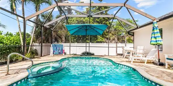Image 2: Screened-in swimming pool featuring a curved design and integrated spa