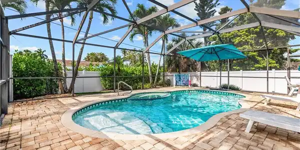 Image 4: Screened enclosure featuring a freeform swimming pool and integrated spa