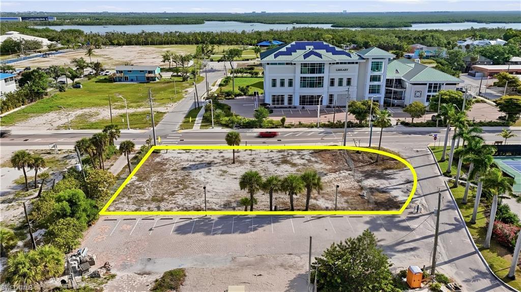 Image 3: Expansive corner lot featuring mature palm trees and direct road frontage - Virtually Edited Image
