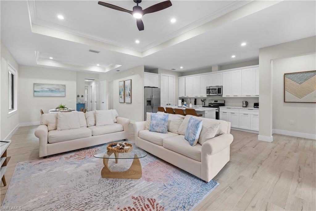 Image 1: Open-concept living area with wood-finish flooring, a tray ceiling, and recessed lighting