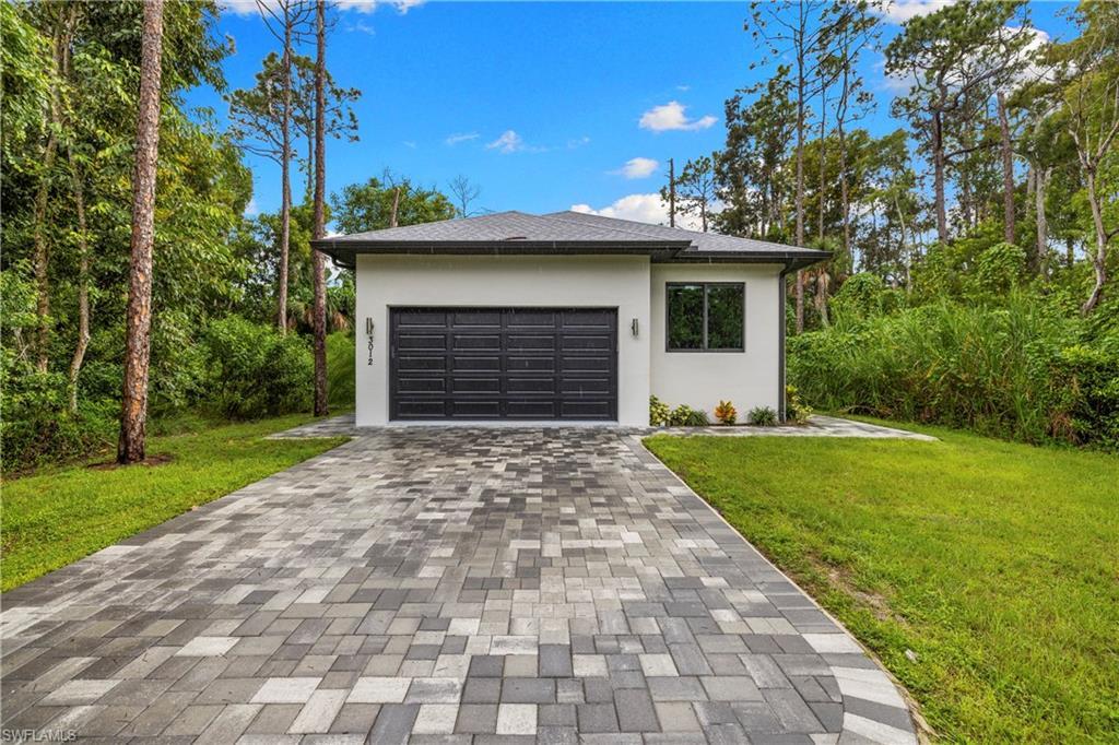 Image 2: Contemporary single-story residence featuring a gray garage door, white stucco exterior, and black-framed windows