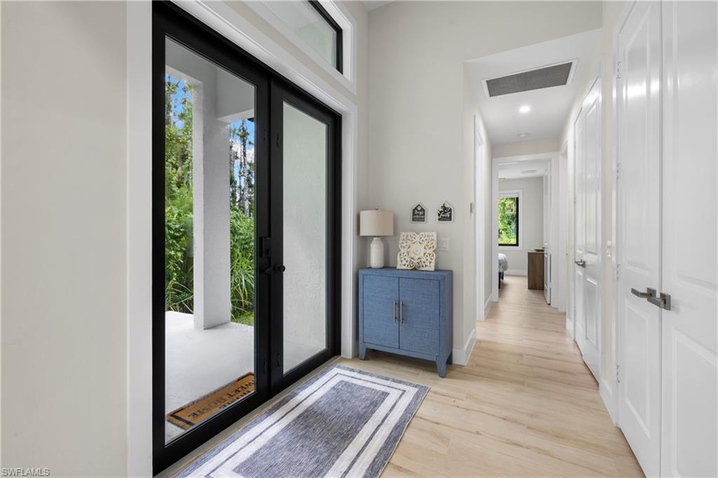 Image 4: Entryway featuring double glass-panel doors with black frames, transom window, recessed lighting, and wood-finish flooring
