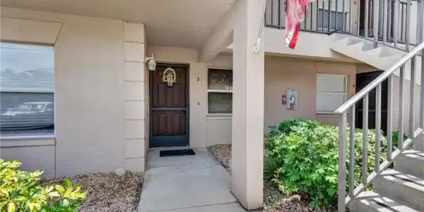 Image 2: Ground-floor entryway featuring a paneled door, exterior wall lantern, and concrete walkway