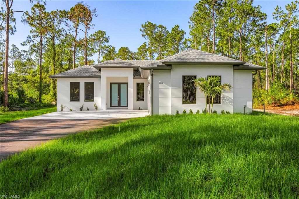 Image 2: Modern single-story residence featuring a white stucco exterior, dark-framed windows, and a covered entry with double glass doors