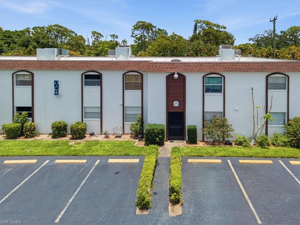 Image 1: Multi-unit building exterior featuring white stucco finish and brown trim accents