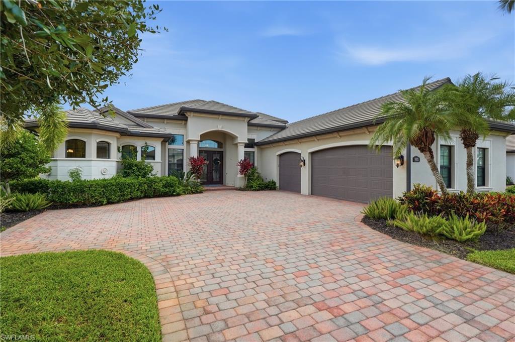 Image 2: Expansive paver driveway leading to a stucco exterior with a tile roof
