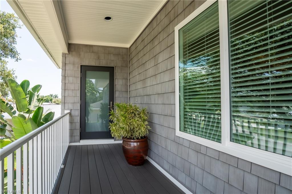 Image 4: Covered front entry featuring a sleek hurricane-rated glass door, low-maintenance decking, and a clean coastal design.