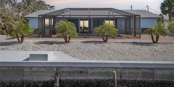 Image 2: Back of house at dusk featuring a sunroom, a lanai, and stucco siding