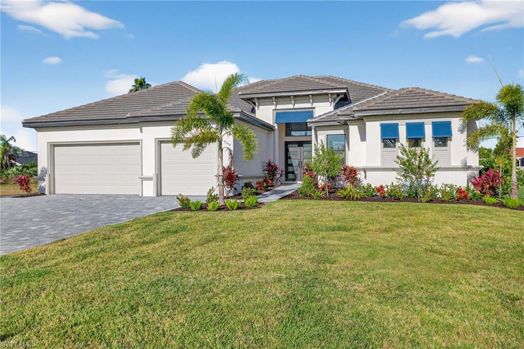 Image 3: Prairie-style home with decorative driveway, a front yard, an attached garage, stucco siding, and a tile roof