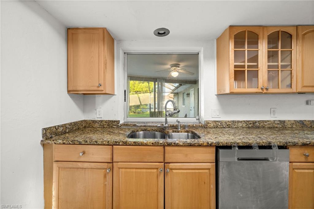 Image 4: Kitchen with dishwasher, dark stone counters, and glass insert cabinets,window overlooking pool