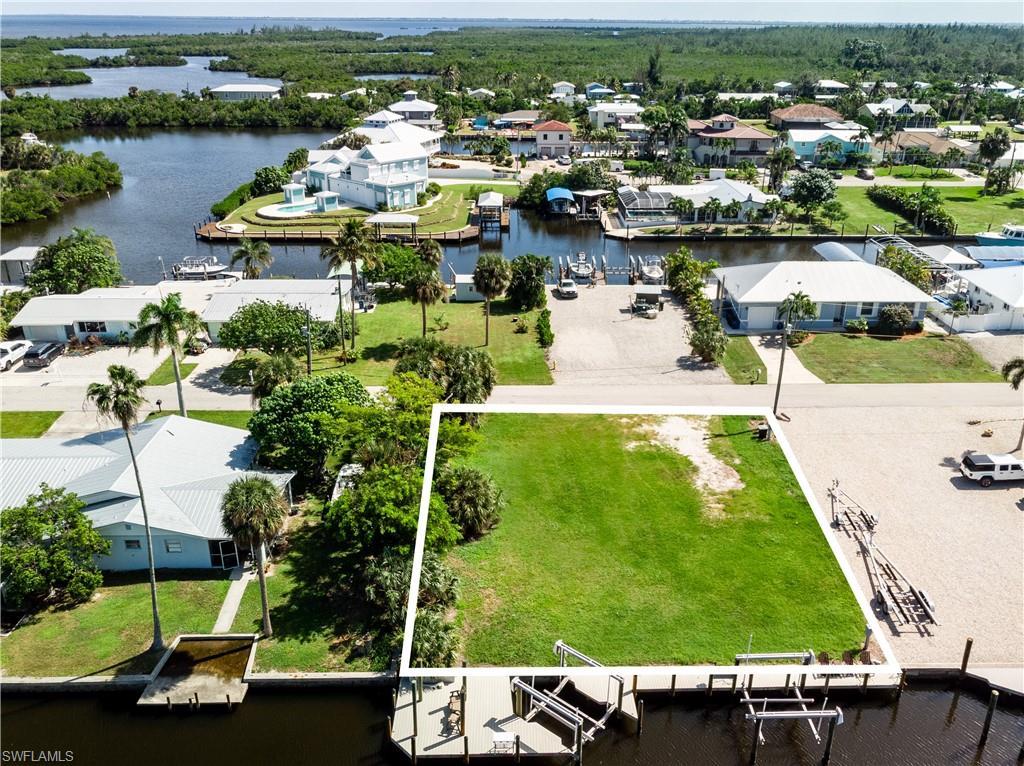 Image 3: Aerial perspective of suburban area featuring a large body of water and property parcel outlined