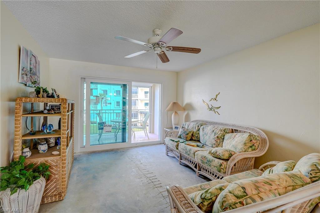 Image 2: Living area with a textured ceiling, unfinished concrete floors, and ceiling fan