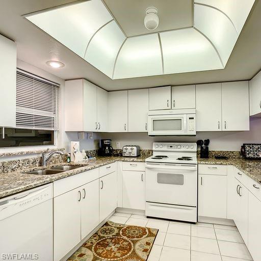 Image 3: Kitchen with white appliances, light tile patterned floors, and white cabinets