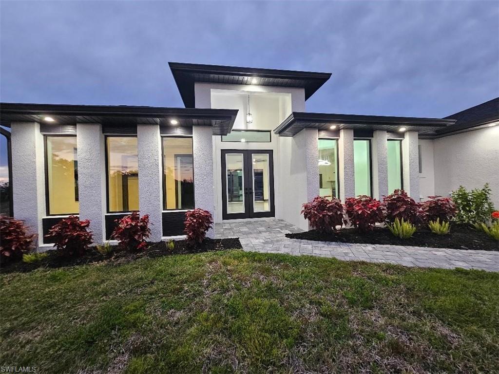 Image 3: Property entrance with a lawn and stucco siding