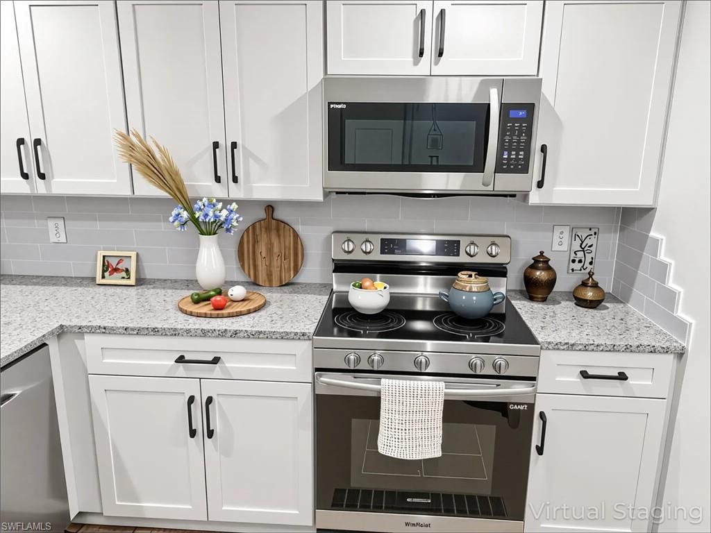 Image 4: Kitchen with appliances with stainless steel finishes, white cabinetry, tasteful backsplash, and light stone counters
