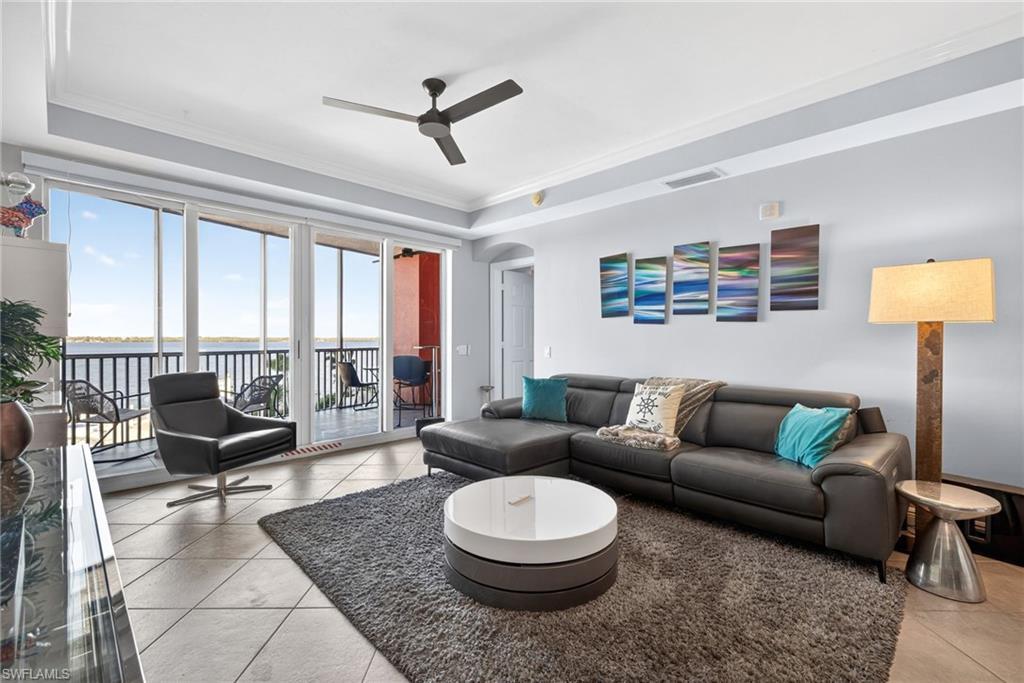 Image 2: Living area featuring a raised ceiling, crown molding, a water view, arched walkways, and light tile patterned floors