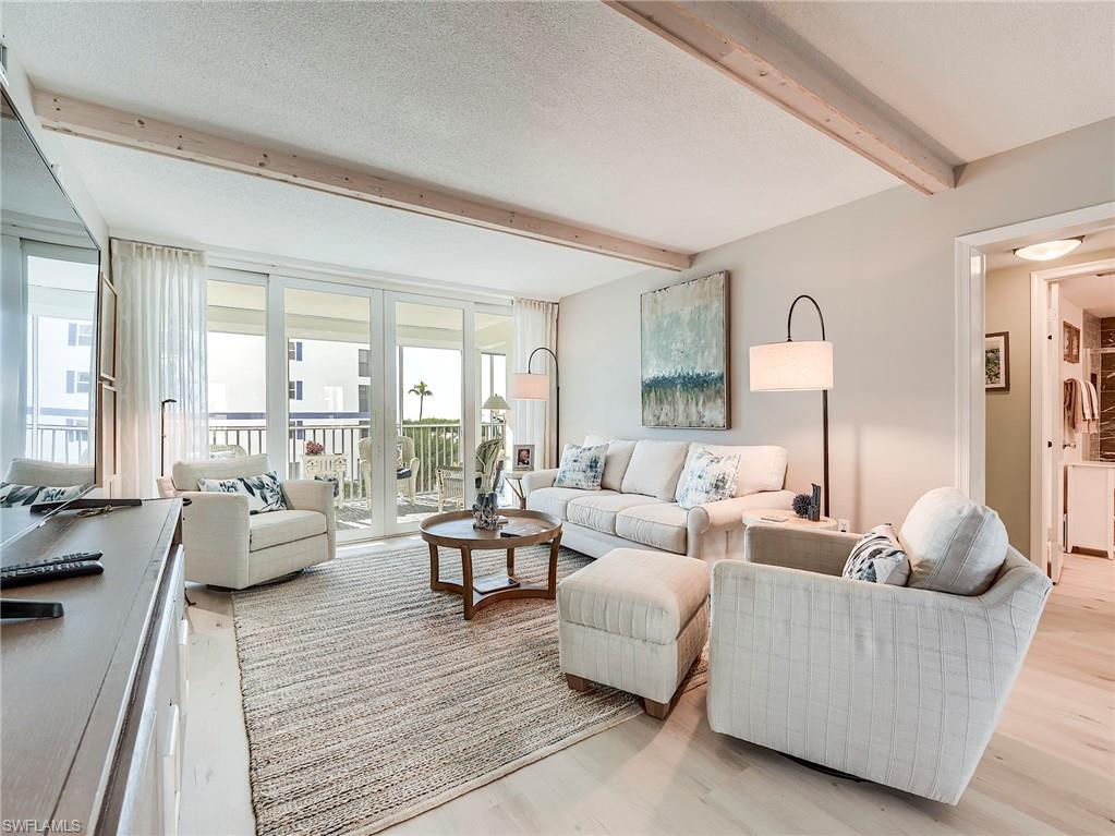 Image 1: Living room featuring beam ceiling, a textured ceiling, and light wood-style flooring