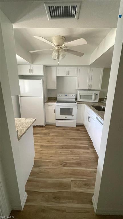 Image 4: Kitchen with white cabinets, white appliances, light wood-style flooring