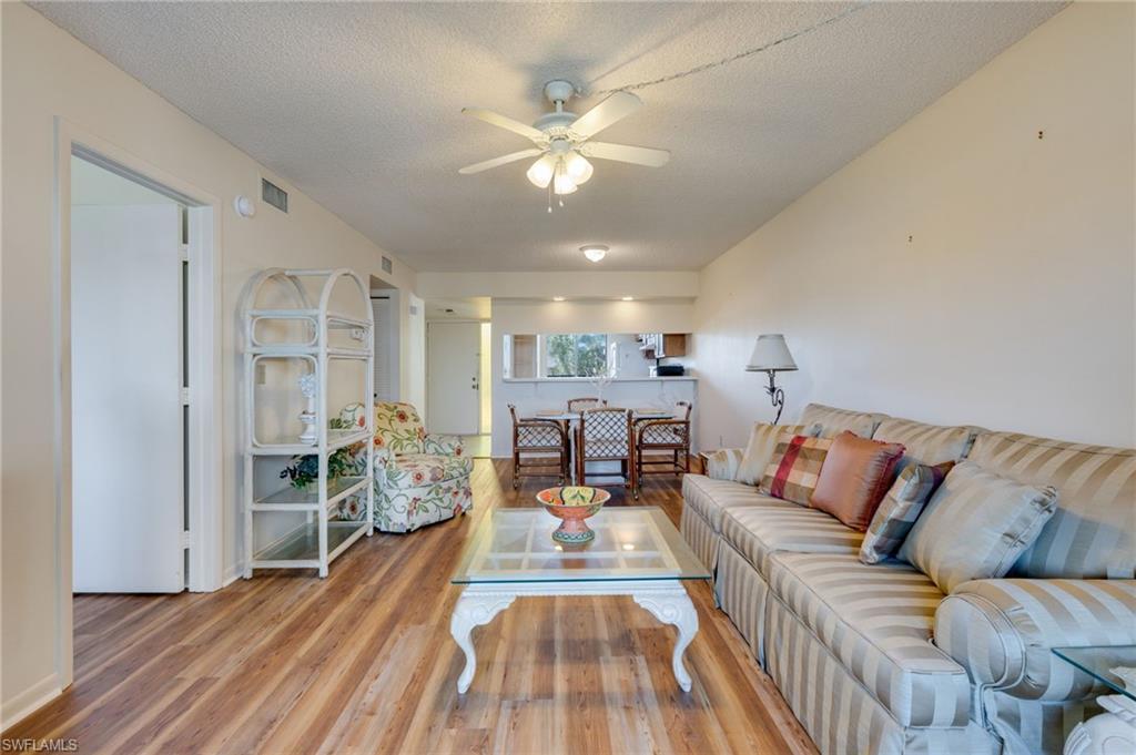 Image 3: Living area with ceiling fan, wood finished floors, and a textured ceiling